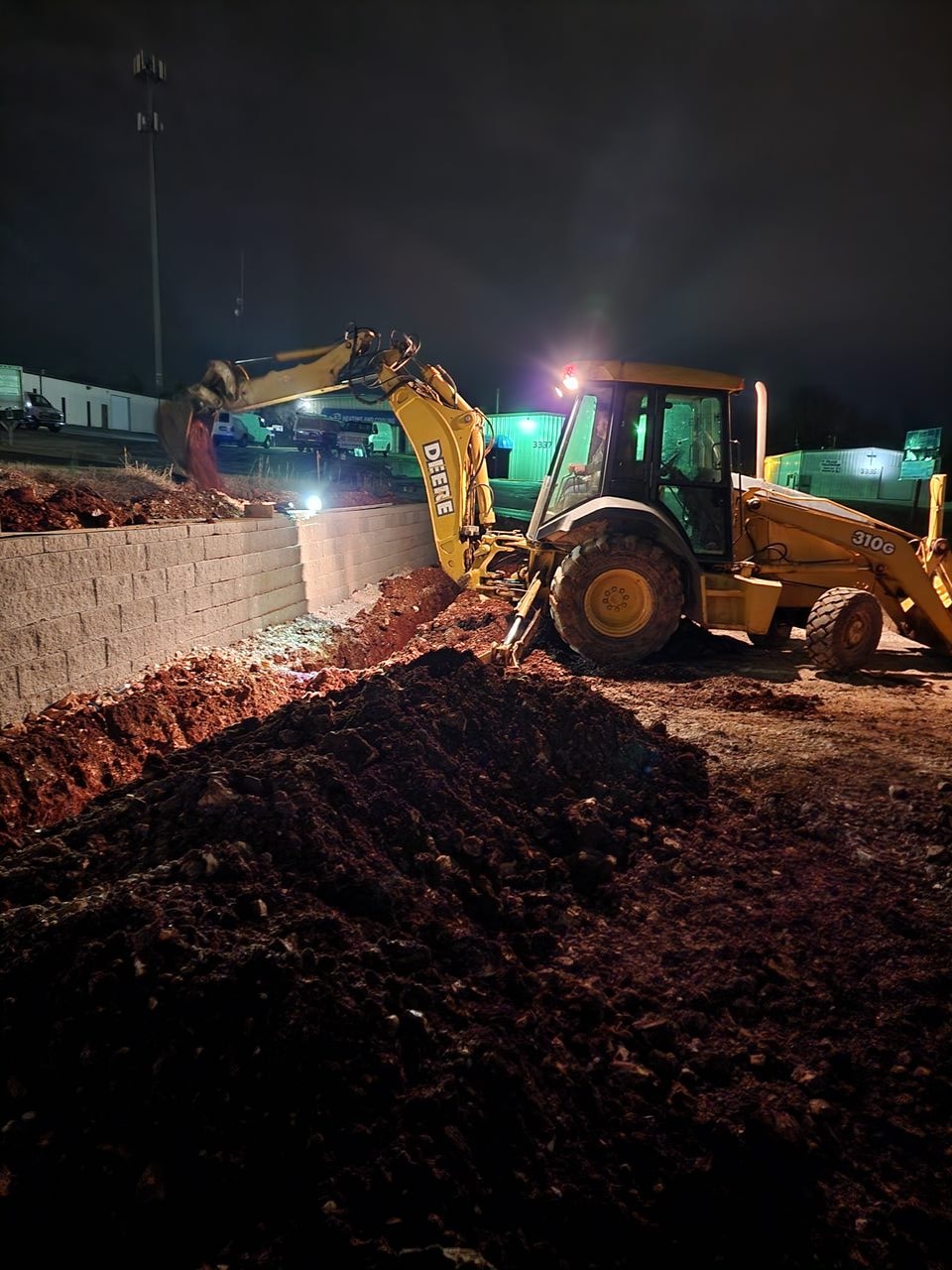 Night excavation work — backhoe and block wall construction by Right Choice Development